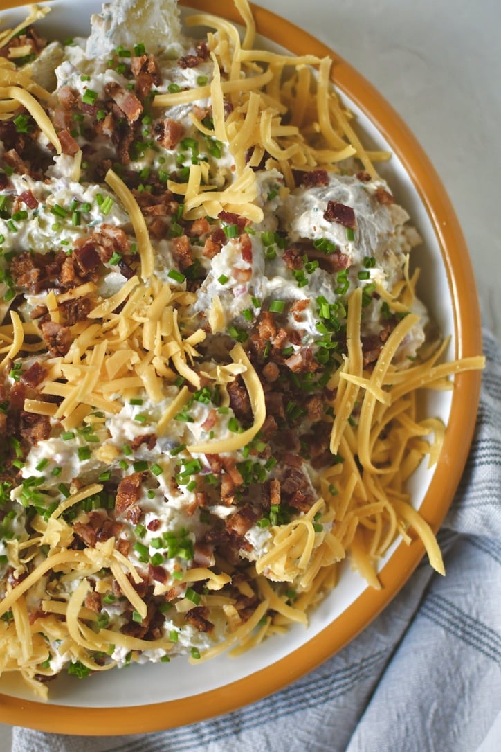 Ranch Potato Salad in a bowl topped with chives, bacon, and cheddar, ready to eat!