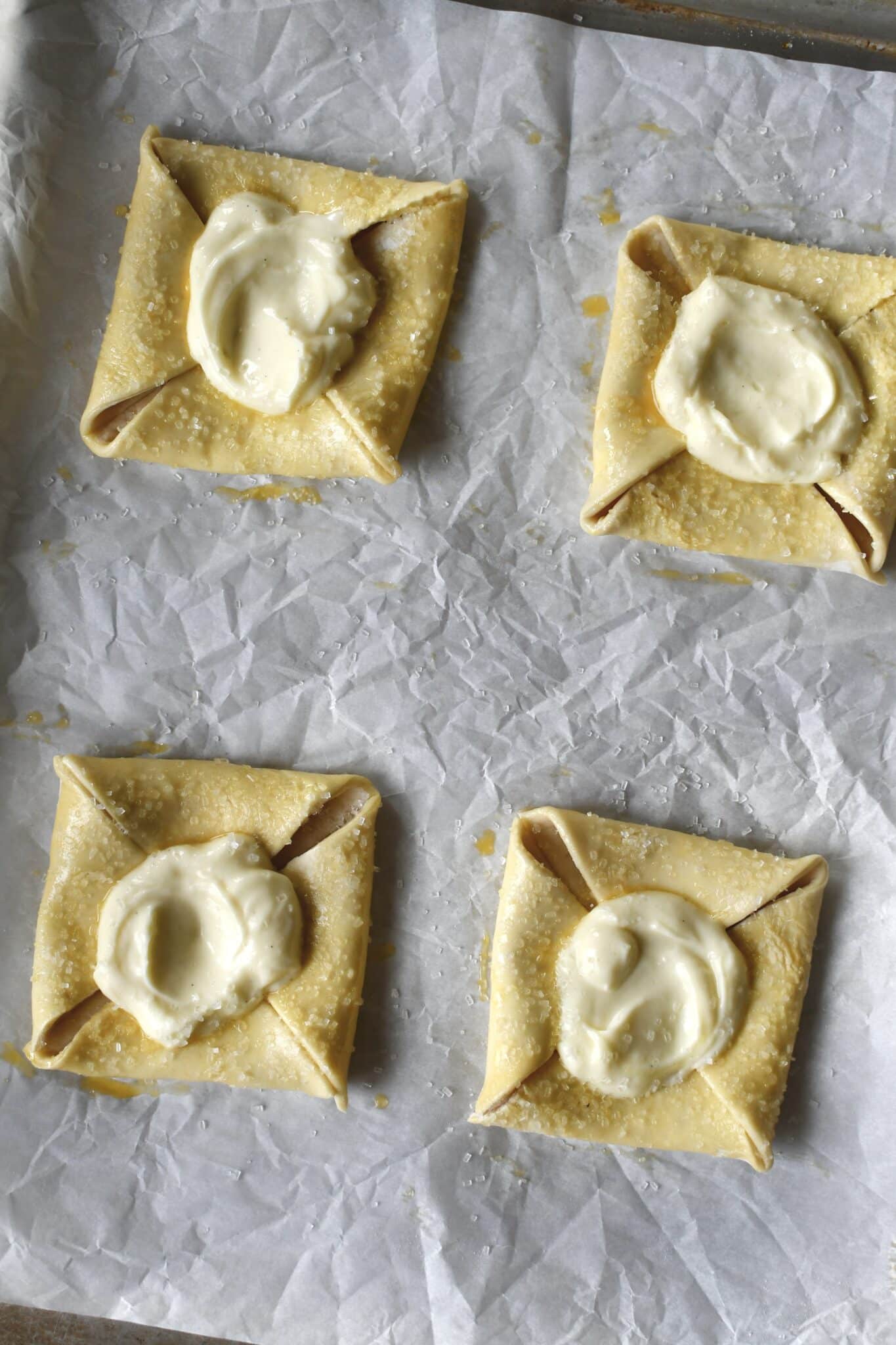 Fully formed and chilled danishes with cream cheese filling on top, before baking.