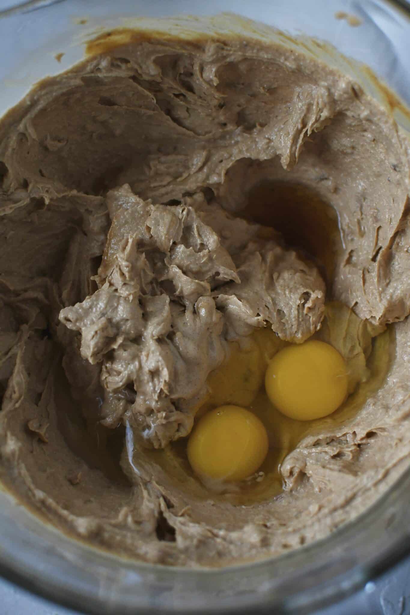 Adding the eggs to the creamed butters and sugars.