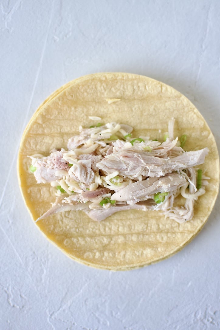 Filling a corn tortilla with the chicken mixture.