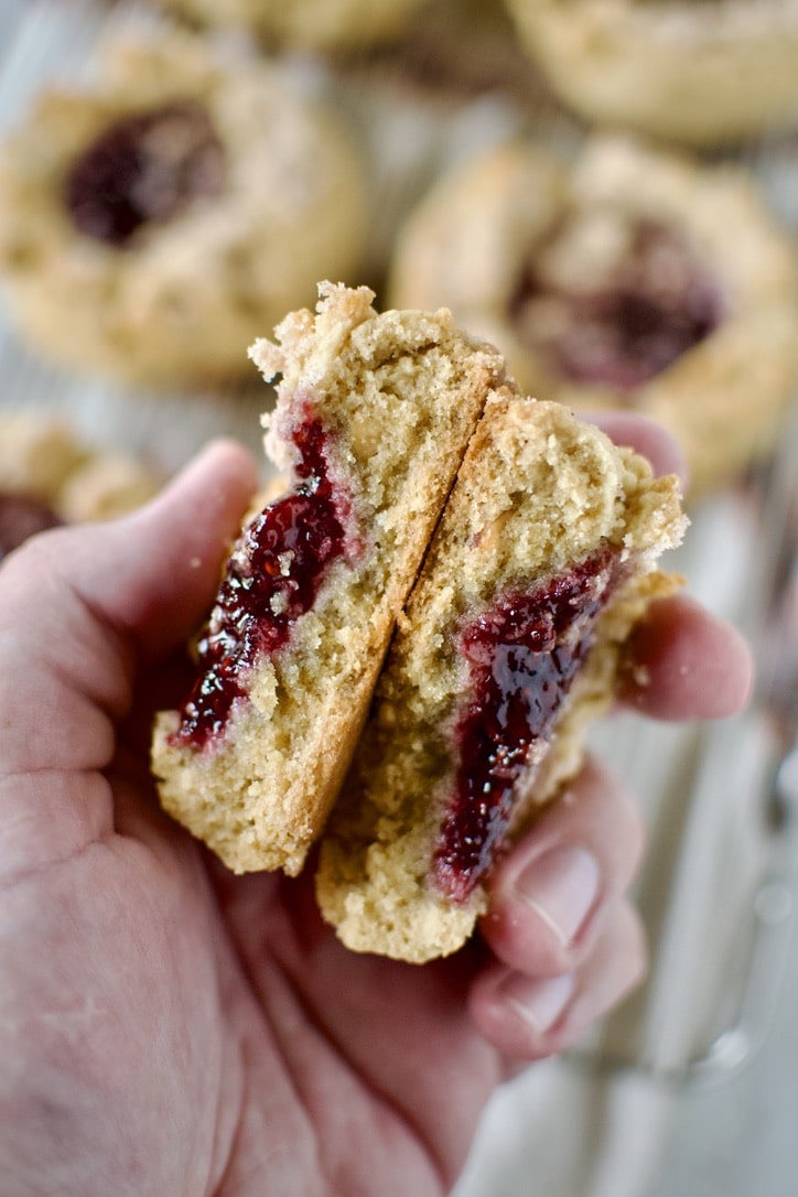 A Peanut Butter and Jelly Cookie broken in half in a hand.