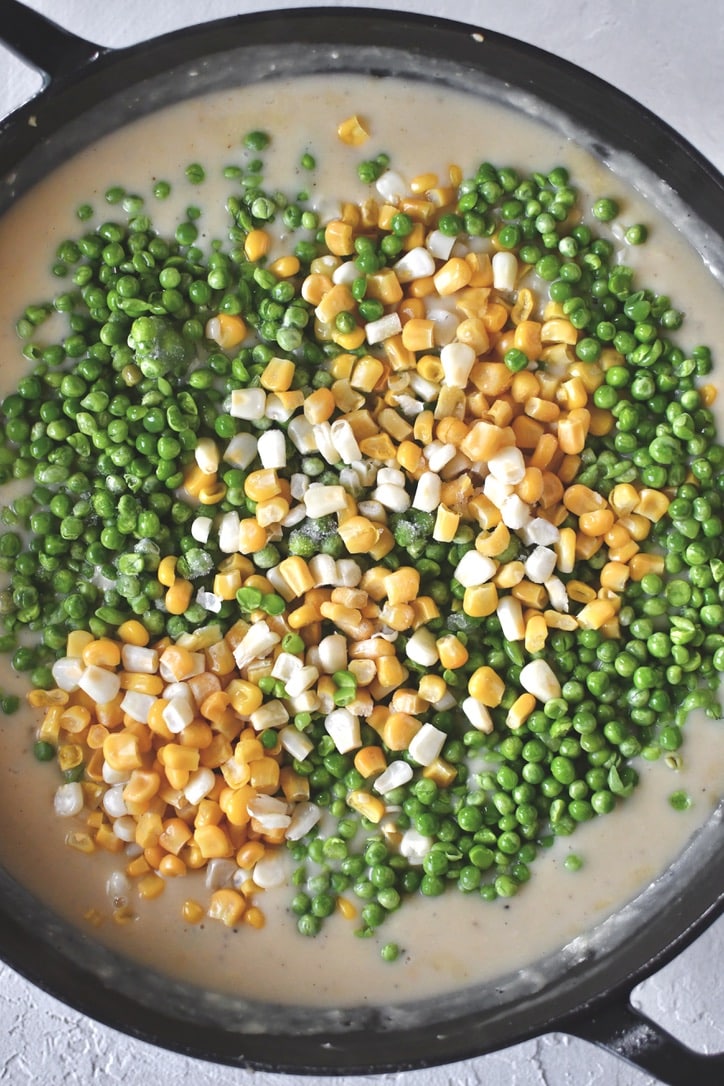 Adding the peas and corn to the sauce.