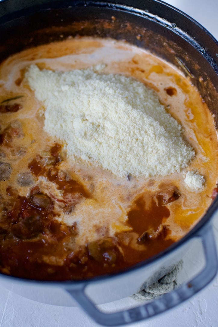 Adding the cream and some grated parmesan to the pot to finish off the sauce.