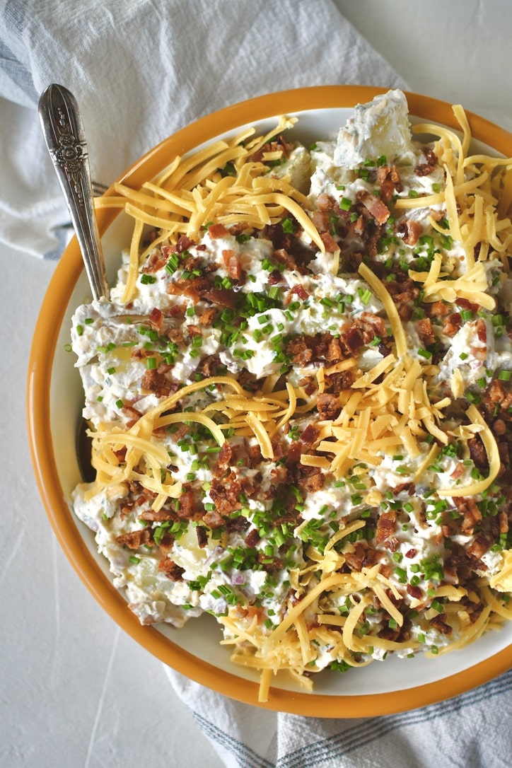 Ranch Potato Salad in a bowl topped with chives, bacon, and cheddar, ready to eat!