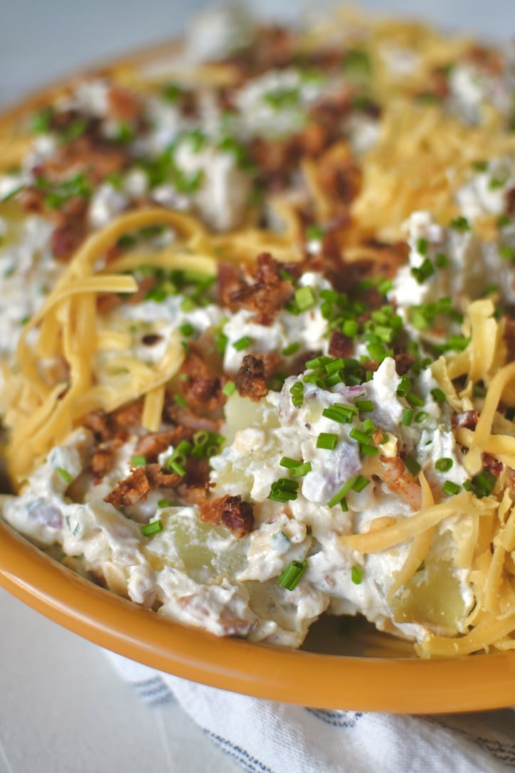 Ranch Potato Salad in a bowl topped with chives, bacon, and cheddar, ready to eat!