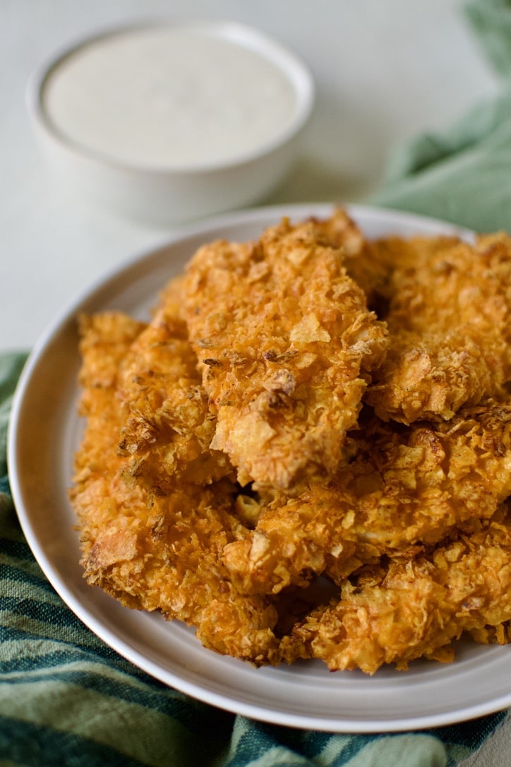 Plate of Dorito Chicken tenders piled up with some ranch on the side to dip them in.