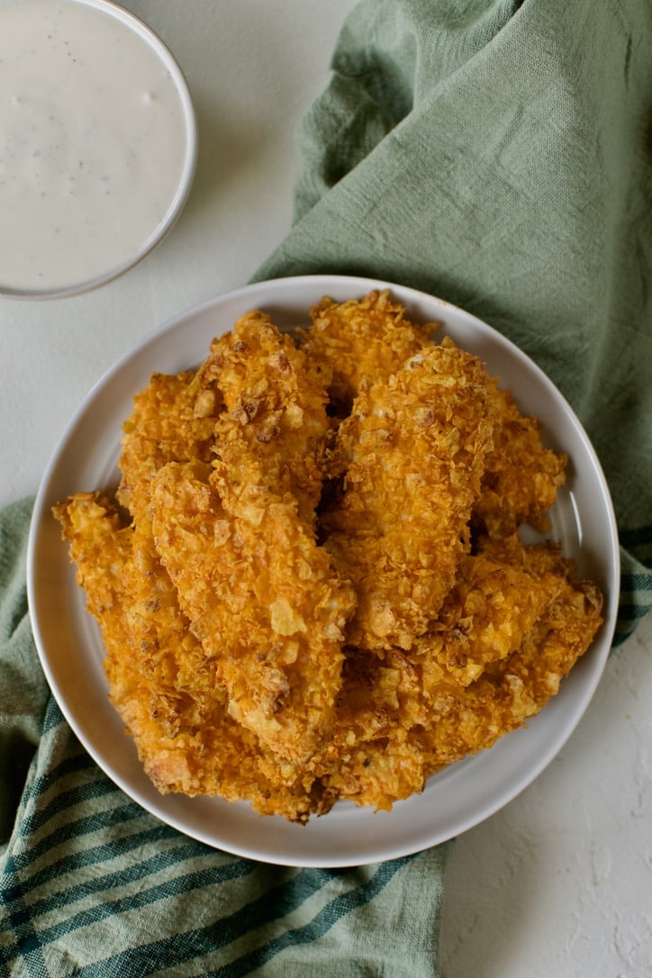 Plate of Dorito Chicken tenders piled up with some ranch on the side to dip them in.