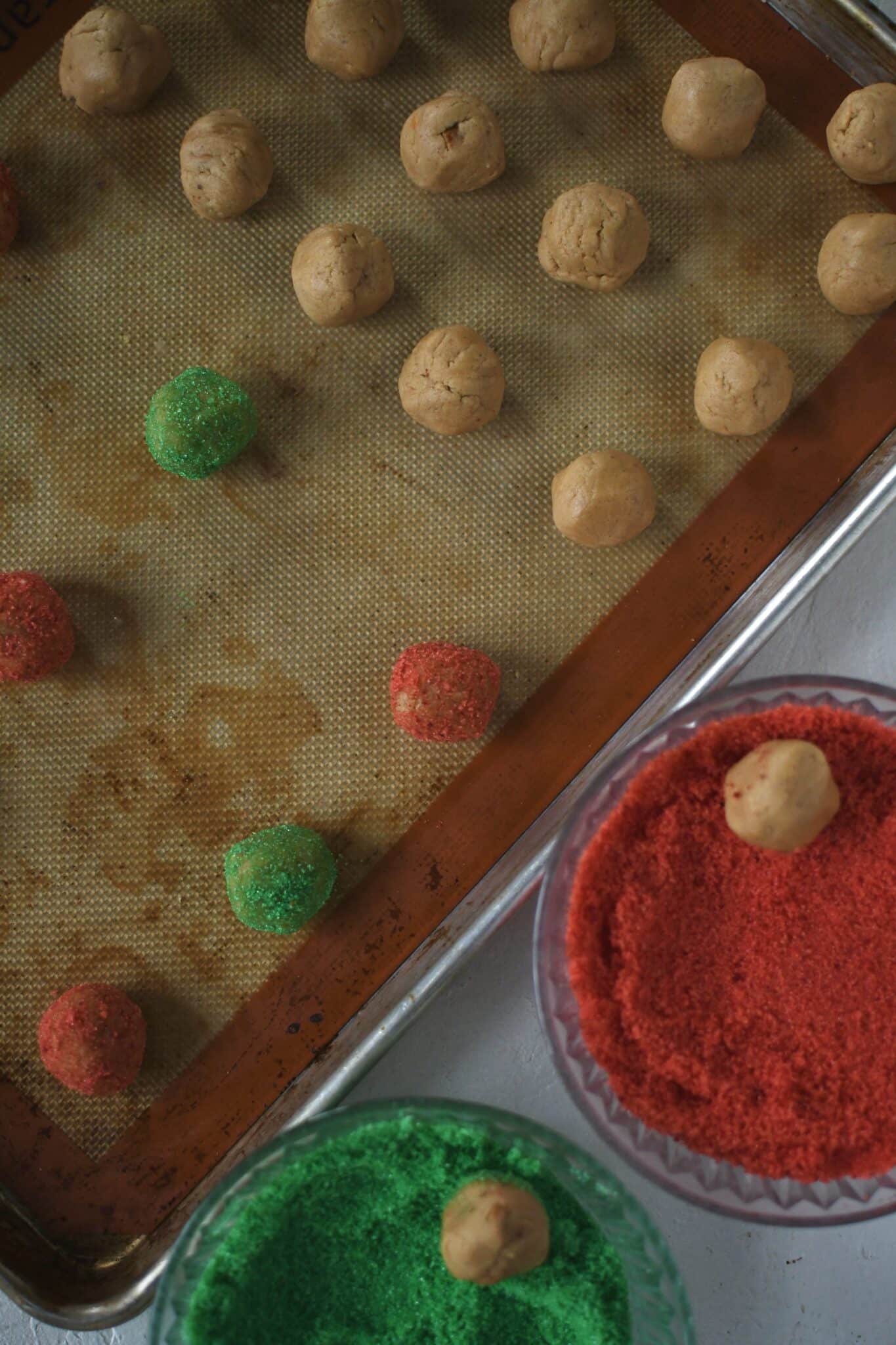 Rolling the cookie dough in red and green sugars before baking.