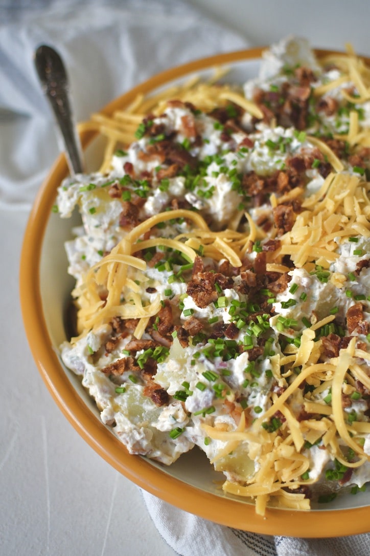 Ranch Potato Salad in a bowl topped with chives, bacon, and cheddar, ready to eat!