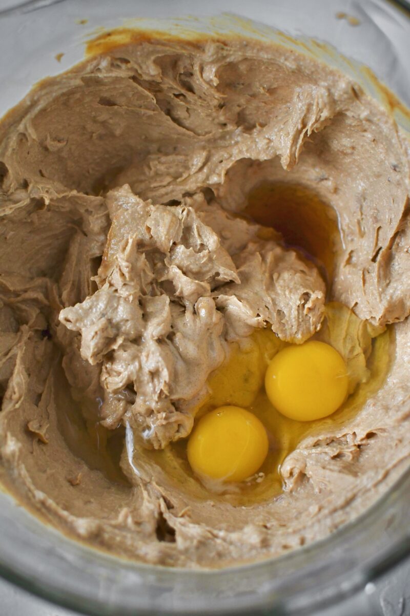 Adding the eggs to the creamed butters and sugars.