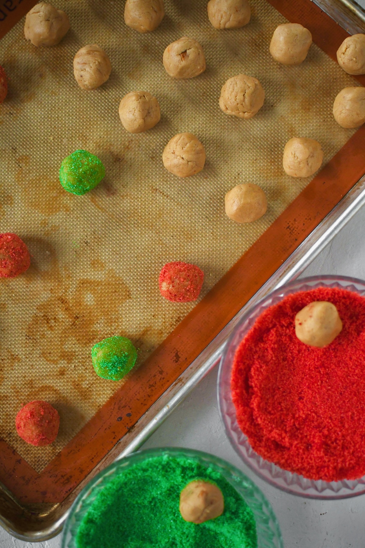 Rolling the cookie dough in red and green sugars before baking.