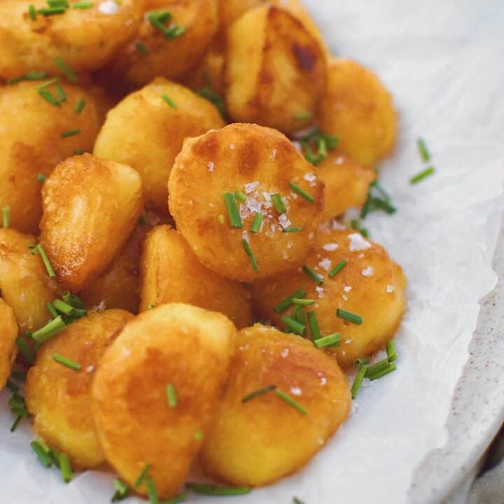 Crispy Roasted Potatoes on a platter topped with flakey sea salt and chopped chives.