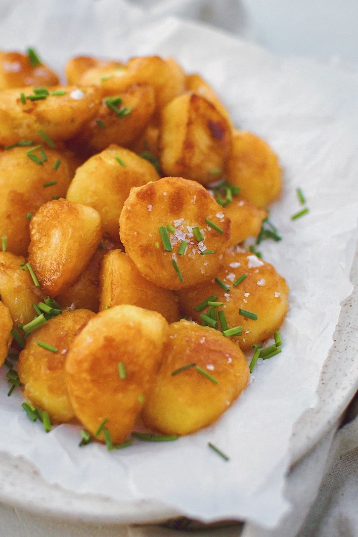 Crispy Roasted Potatoes on a platter topped with flakey sea salt and chopped chives.