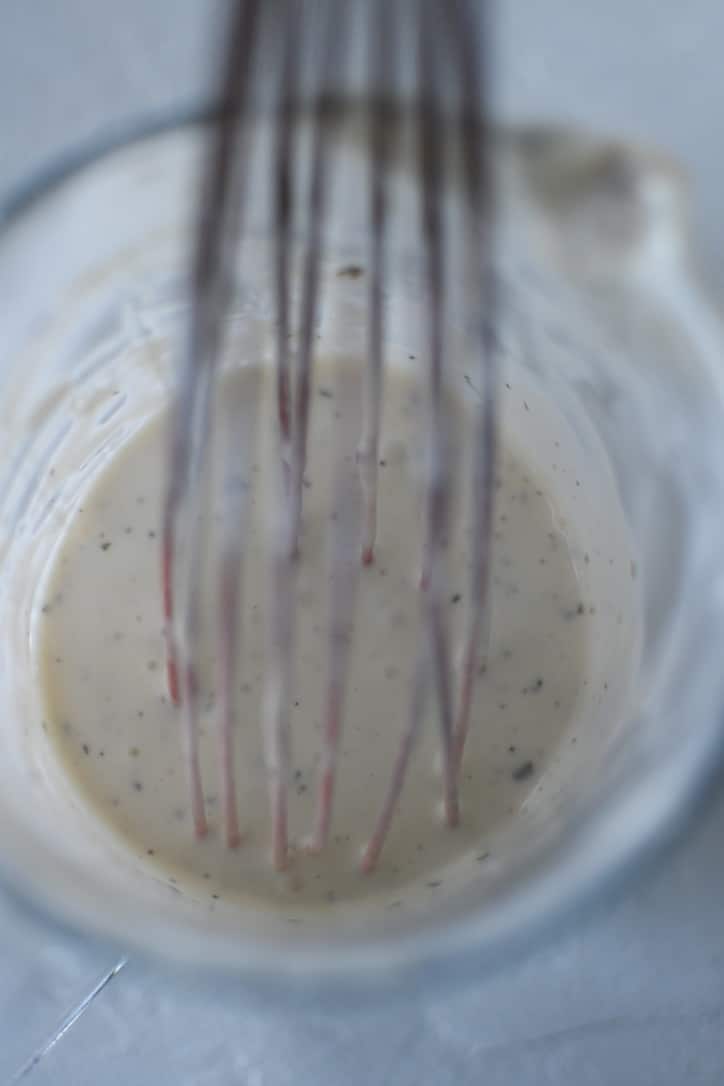 Stirring up the ranch in a measuring cup before transferring it to a clean jar.