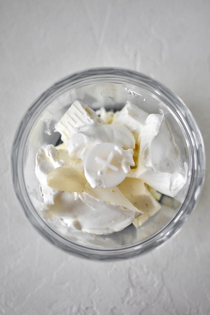 Feta, sour cream, and garlic added to a mini food processor, before blending.
