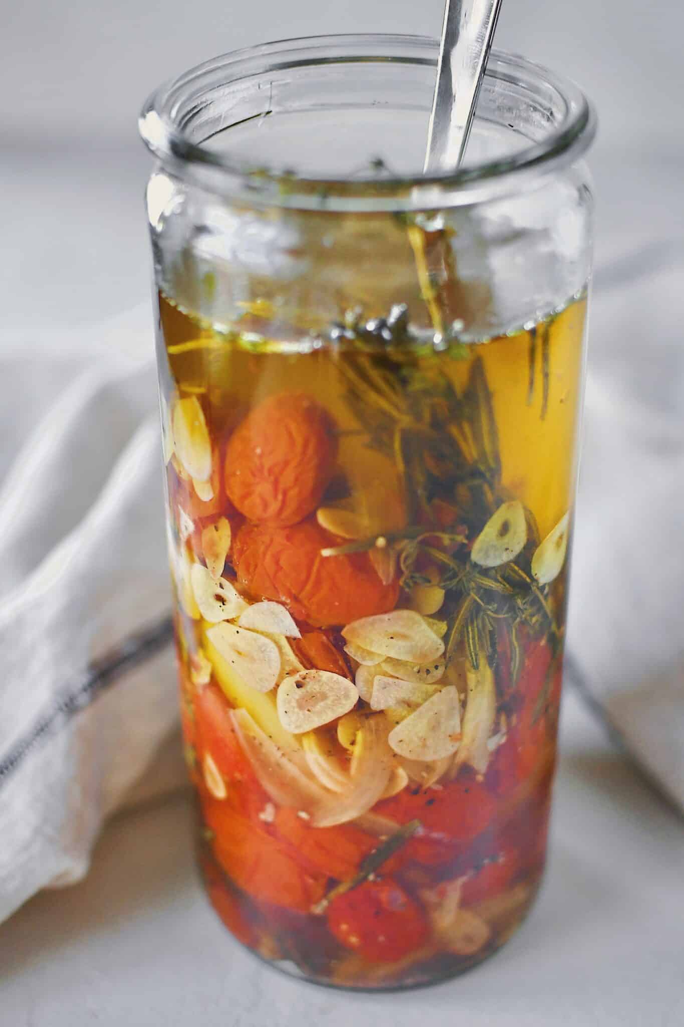 Tomato Confit in a jar covered in oil, ready to be stored.