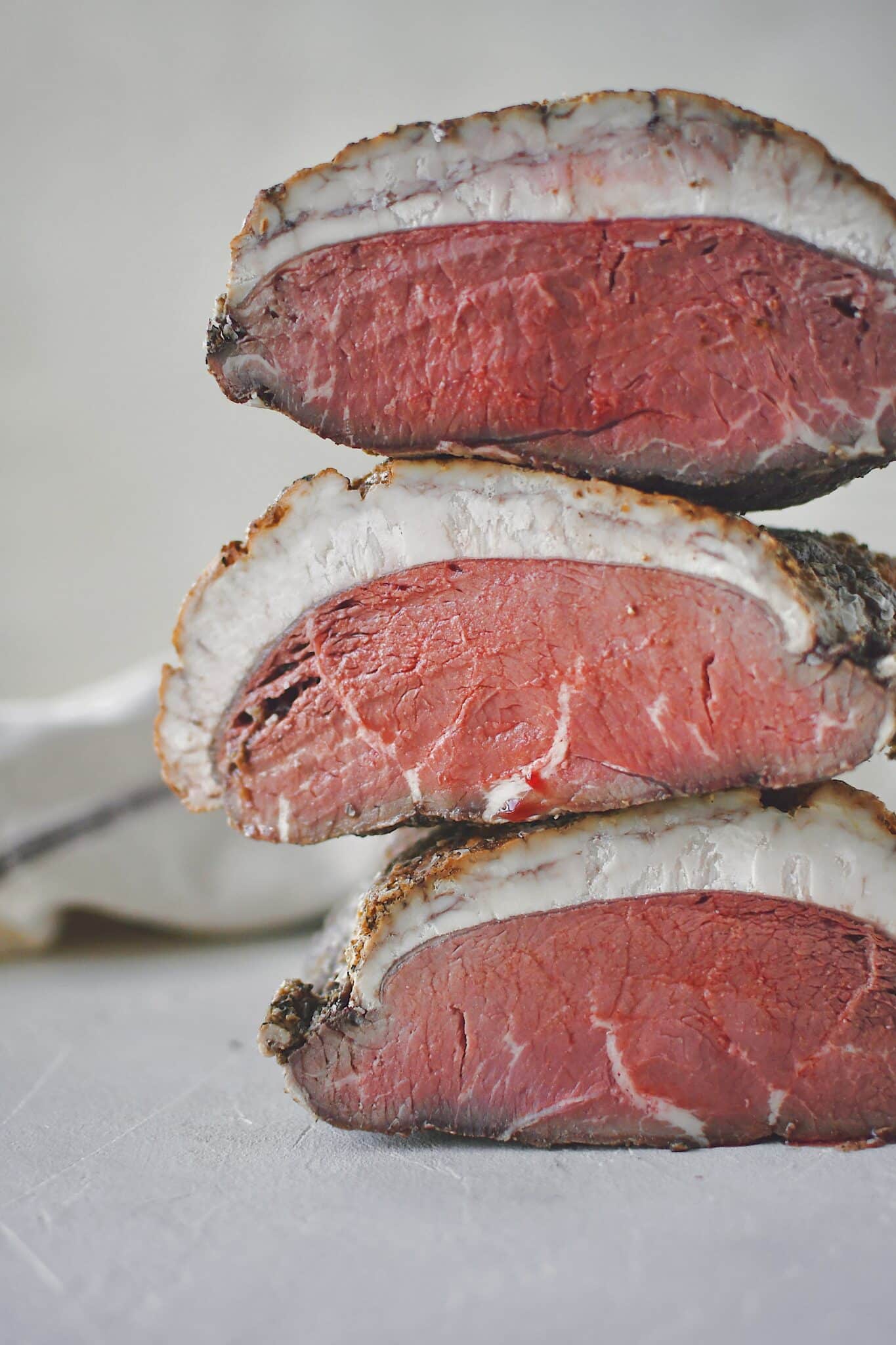 Seasoned beef after roasting and sliced in half to show the perfectly cooked center after chilling.