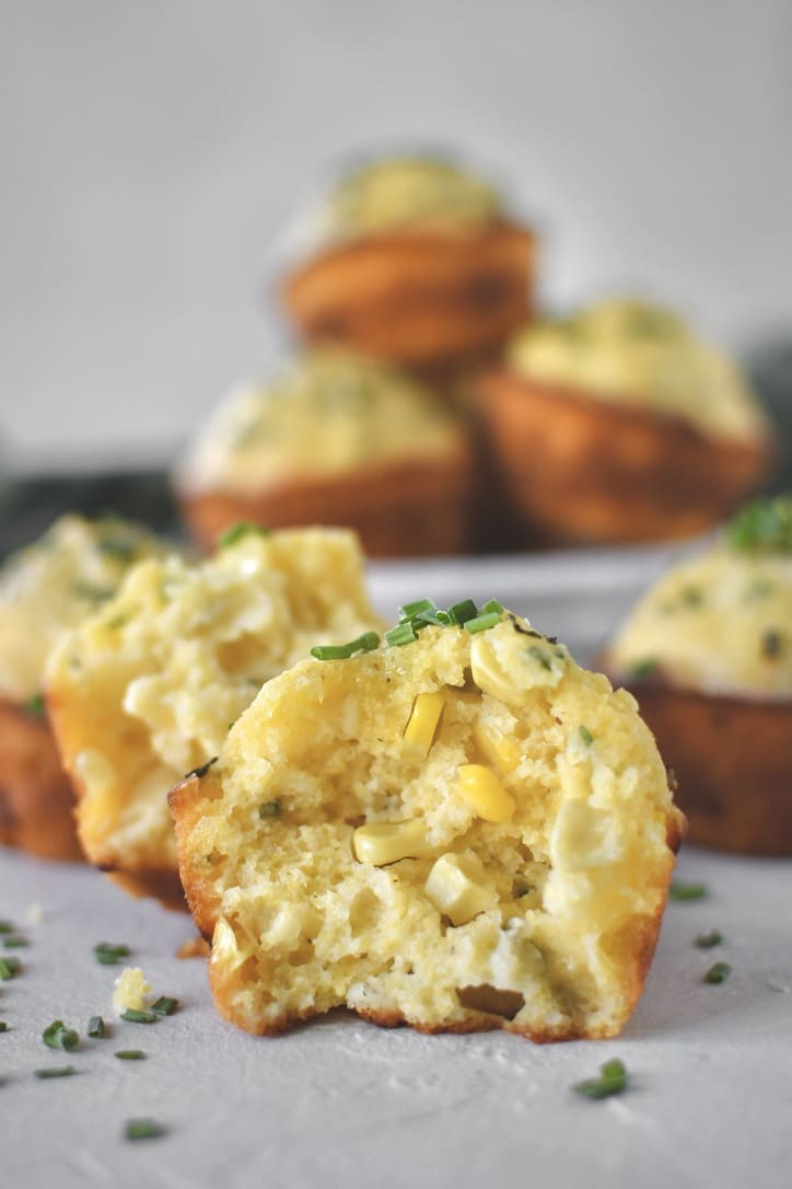 Cornbread Muffins scattered on counter, one split in half.