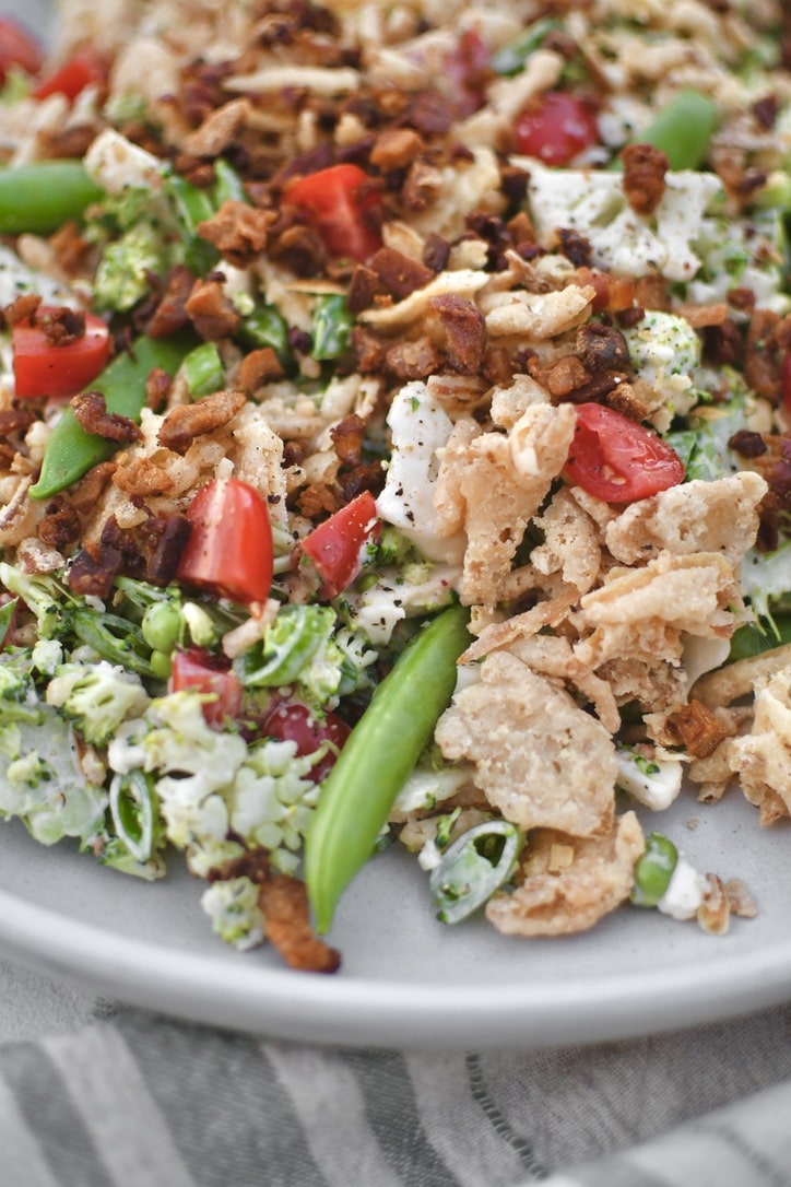 Snap Pea Salad on a platter topped with bacon bits and crispy onions ready to eat.