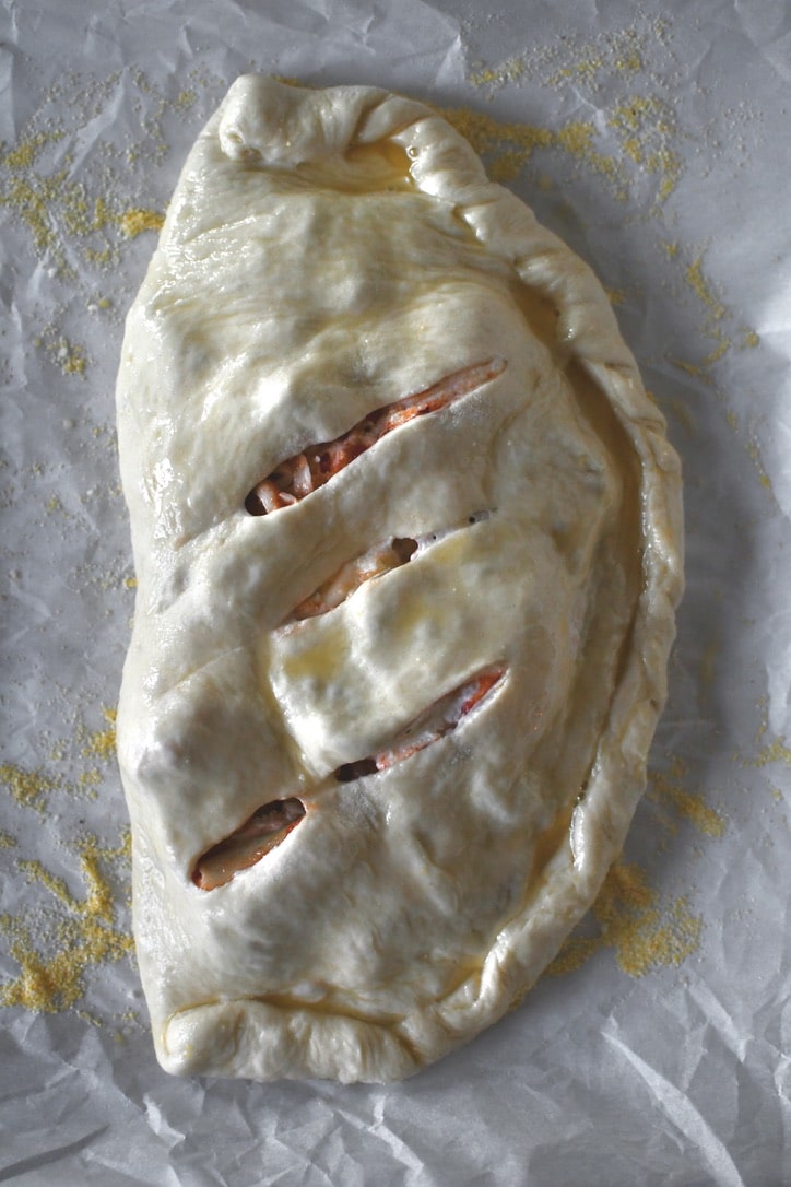 Folded over calzone dough with three slits in it to release steam, brushed in egg wash.