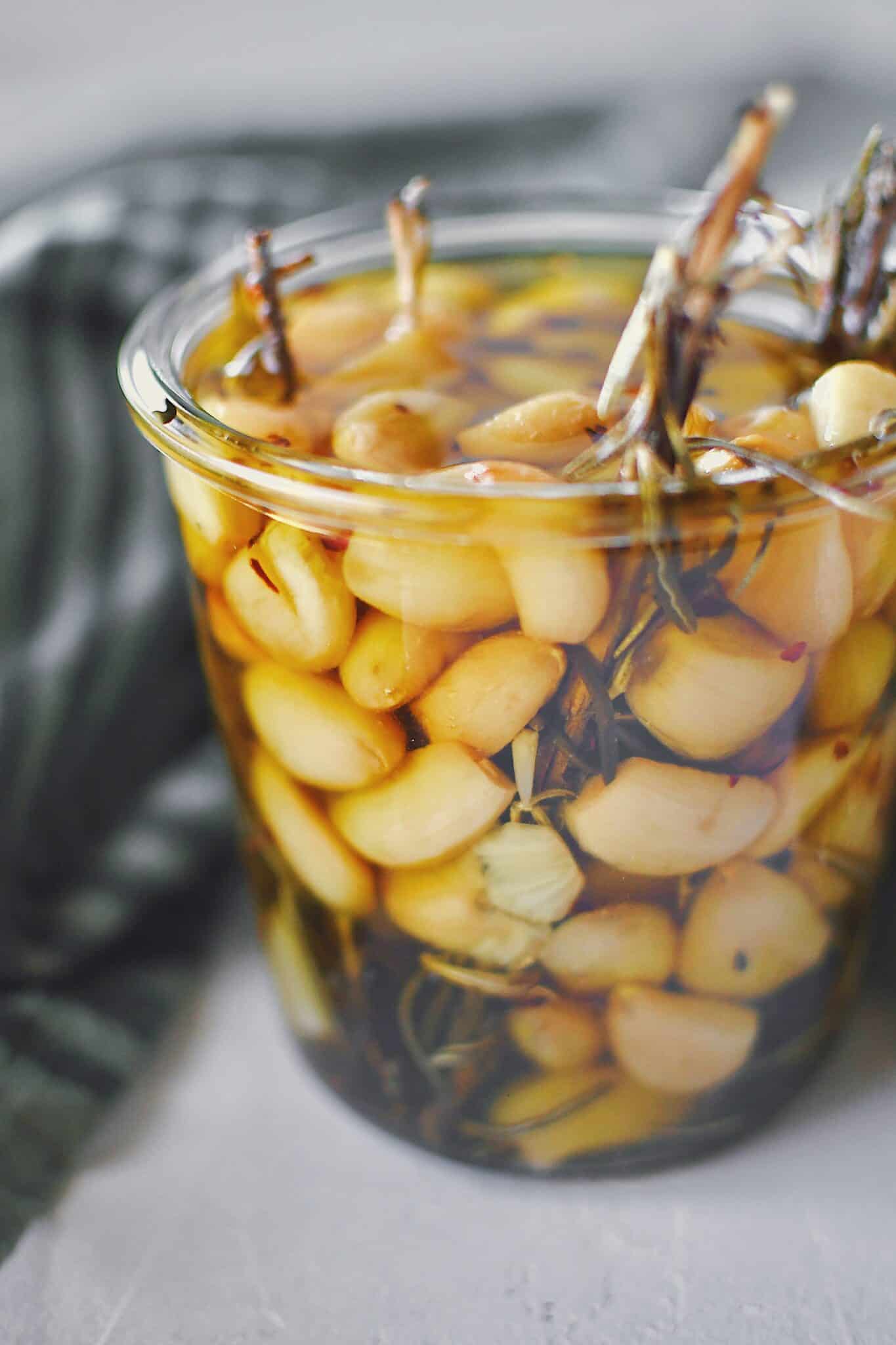 Garlic Confit in a jar covered with olive oil, ready to eat.