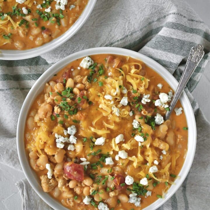 Buffalo Chicken Chili served in a bowl, topped with chives, blue cheese, and cheddar cheese.