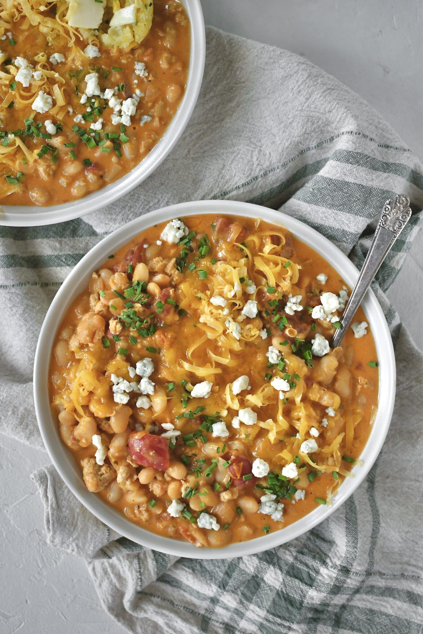 Buffalo Chicken Chili served in a bowl, topped with chives, blue cheese, and cheddar cheese.