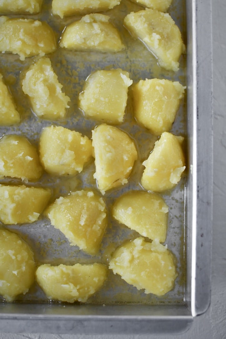 Placing the tossed & "fuzzed" potatoes into a pan that has been warmed in the oven with hot oil in it.