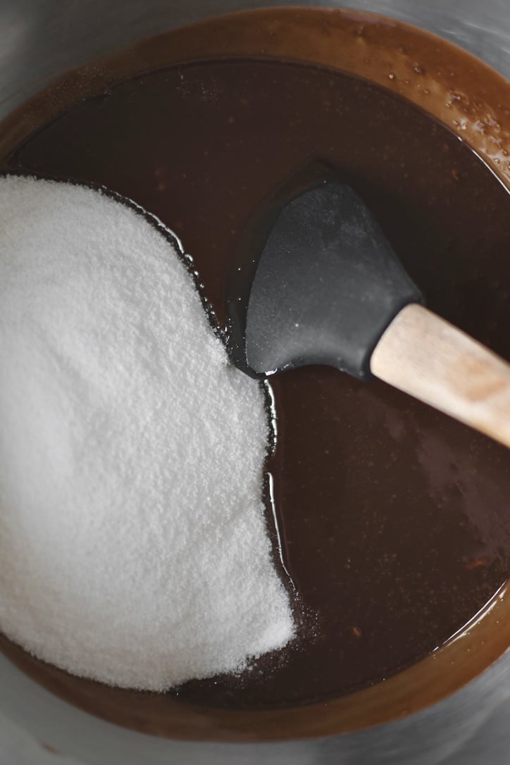 Adding the sugar to he melted butter and chocolate to start making the brownie batter.