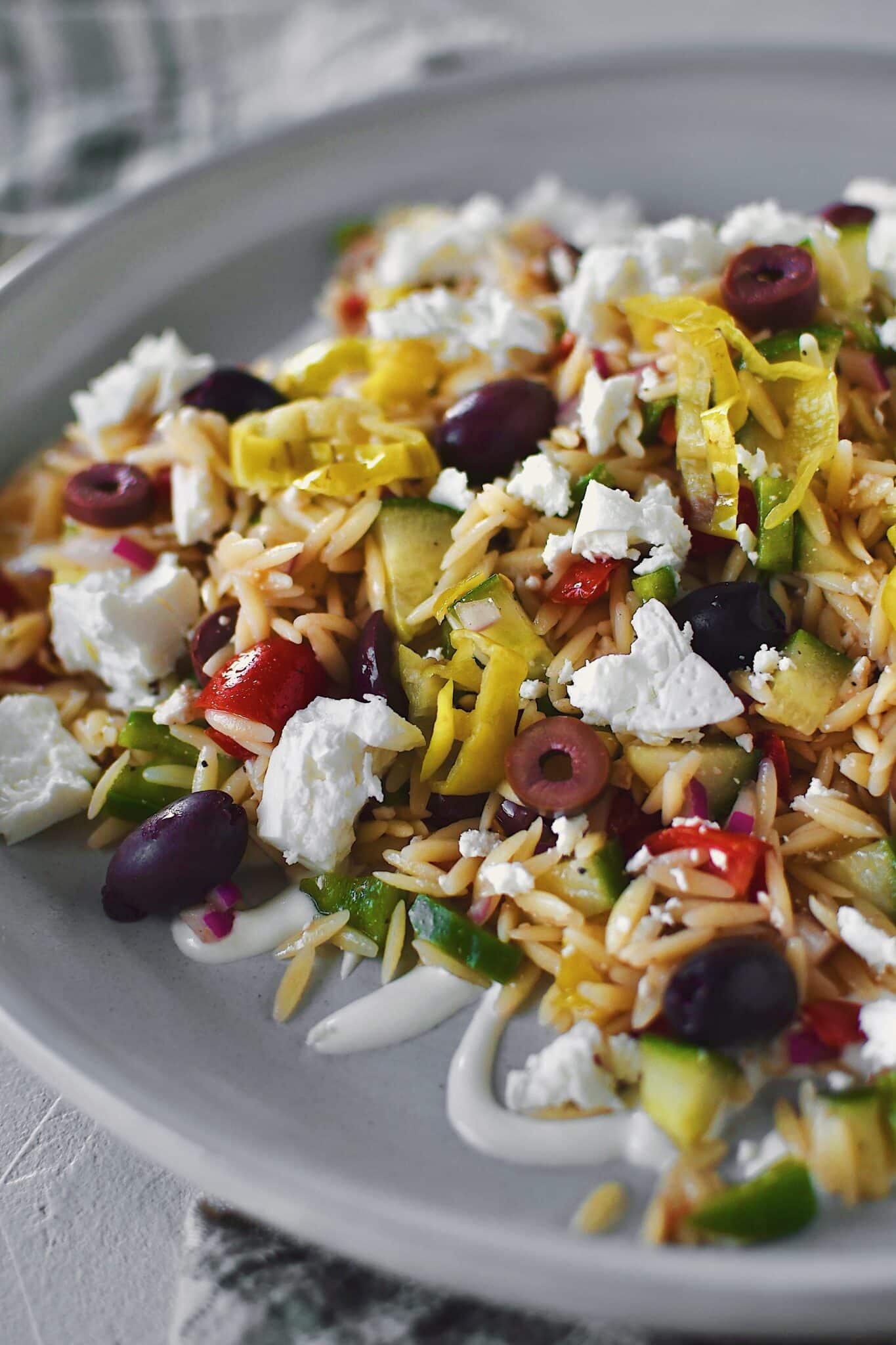 Greek Pasta Salad on a platter, topped with extra feta, ready to be enjoyed!