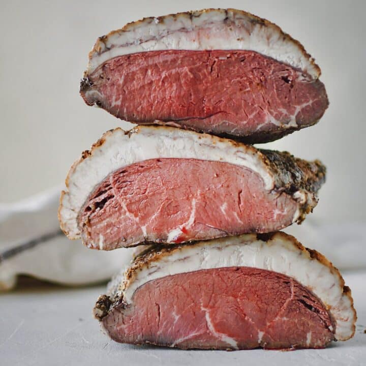 Seasoned beef after roasting and sliced in half to show the perfectly cooked center after chilling.