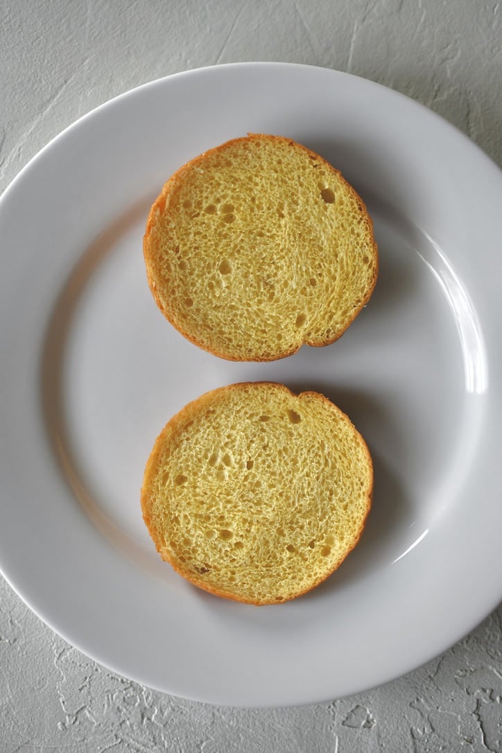 Assembling a roast beef sandwich; starting with a toasted bun on a plate.