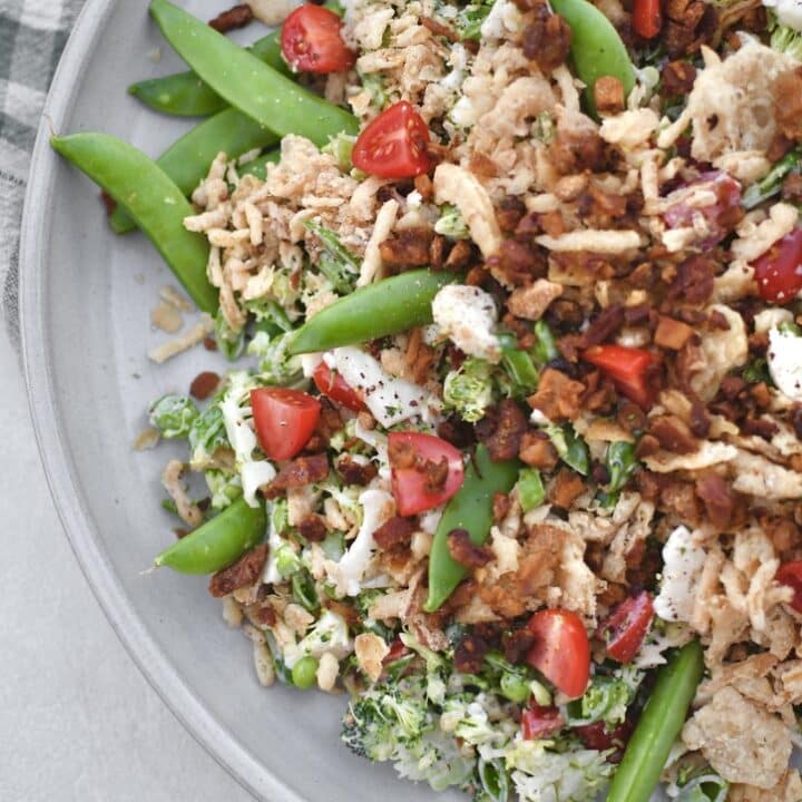 Snap Pea Salad on a platter topped with bacon bits and crispy onions ready to eat.