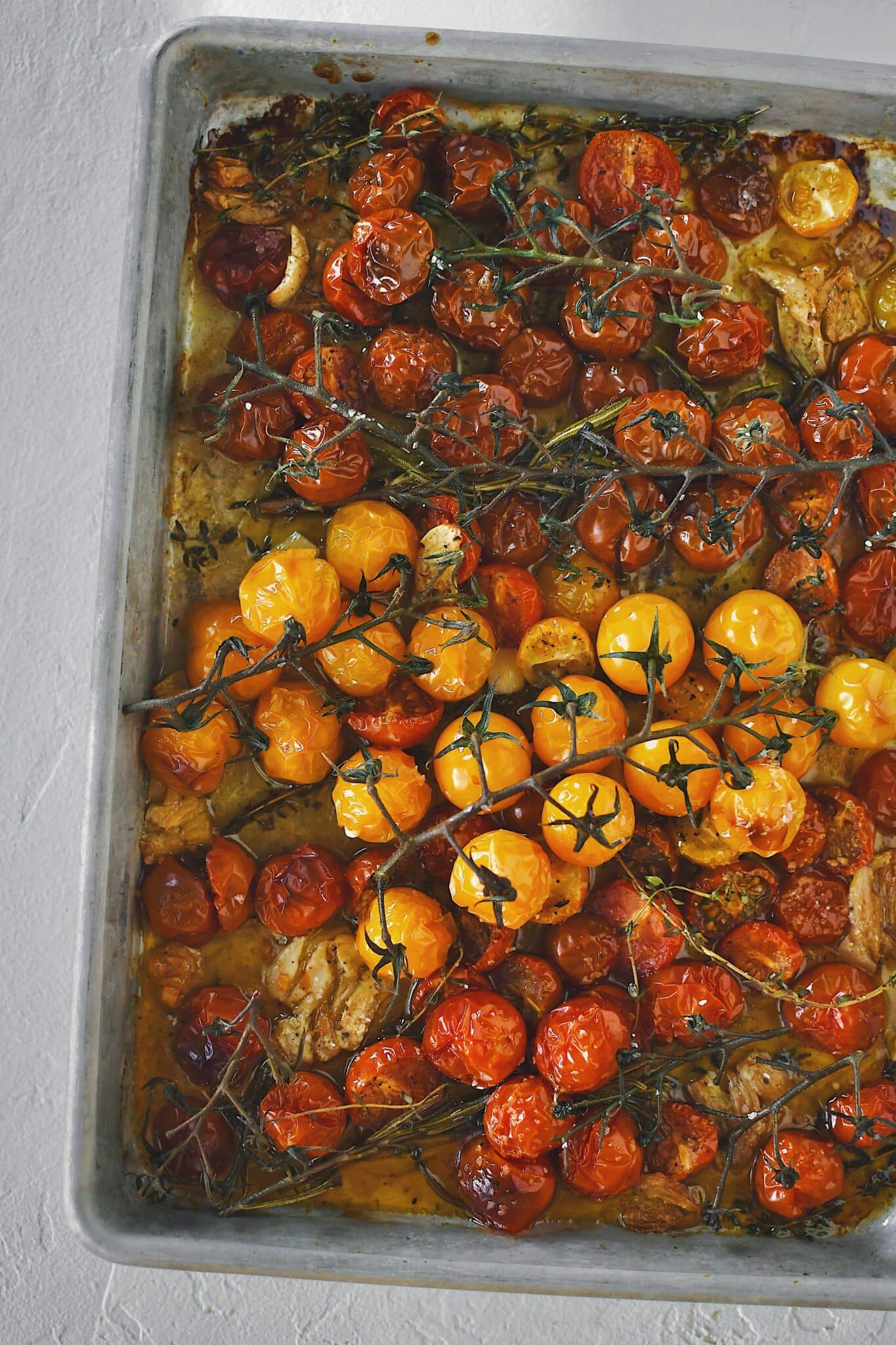 Seasoned cherry tomatoes, garlic, and herbs, after roasting.