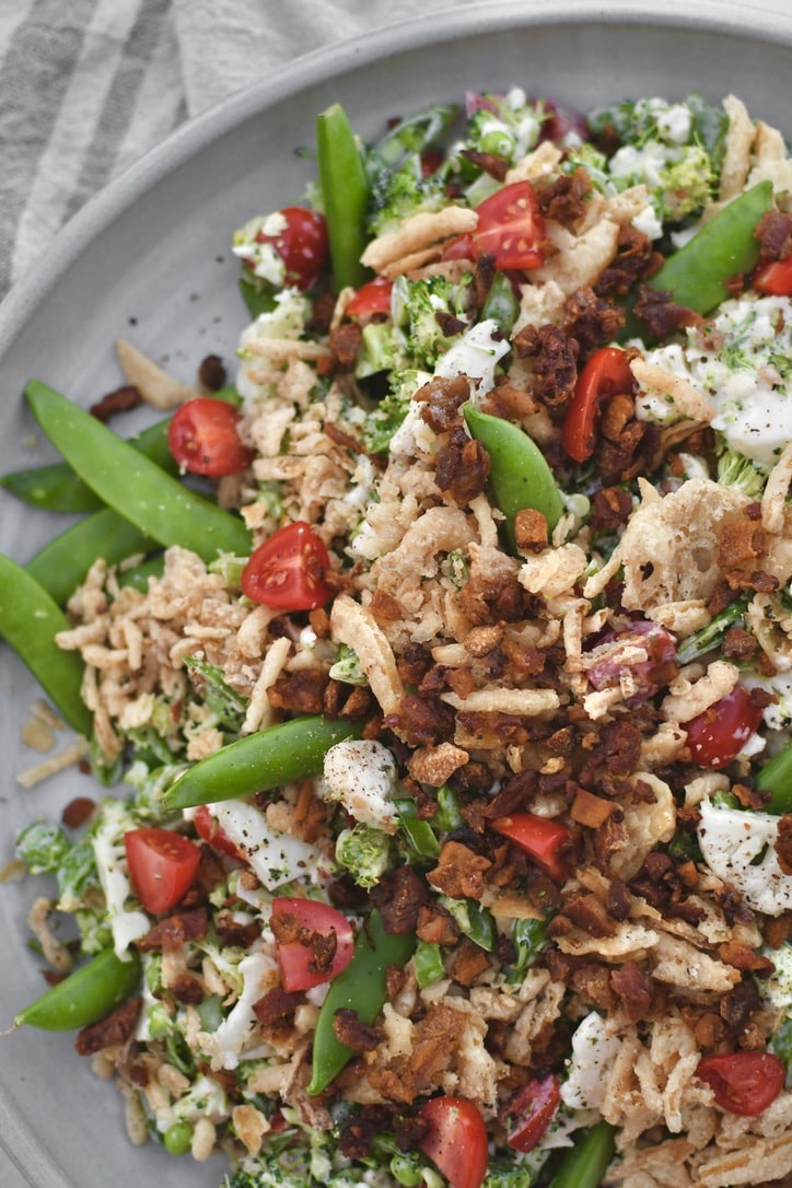 Snap Pea Salad on a platter topped with bacon bits and crispy onions ready to eat.