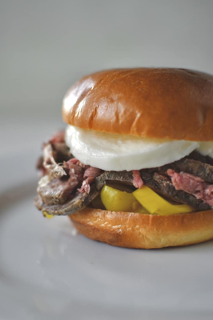 Fully assembled roast beef sandwich on a plate ready to eat.