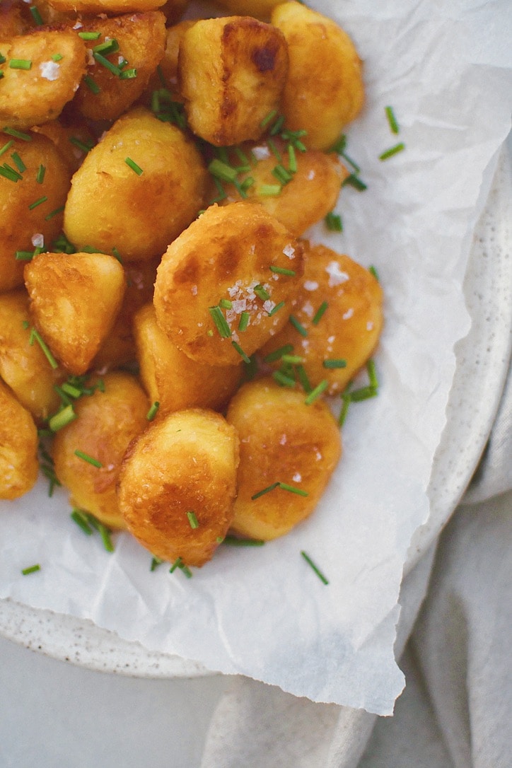 Crispy Roasted Potatoes on a platter topped with flakey sea salt and chopped chives.