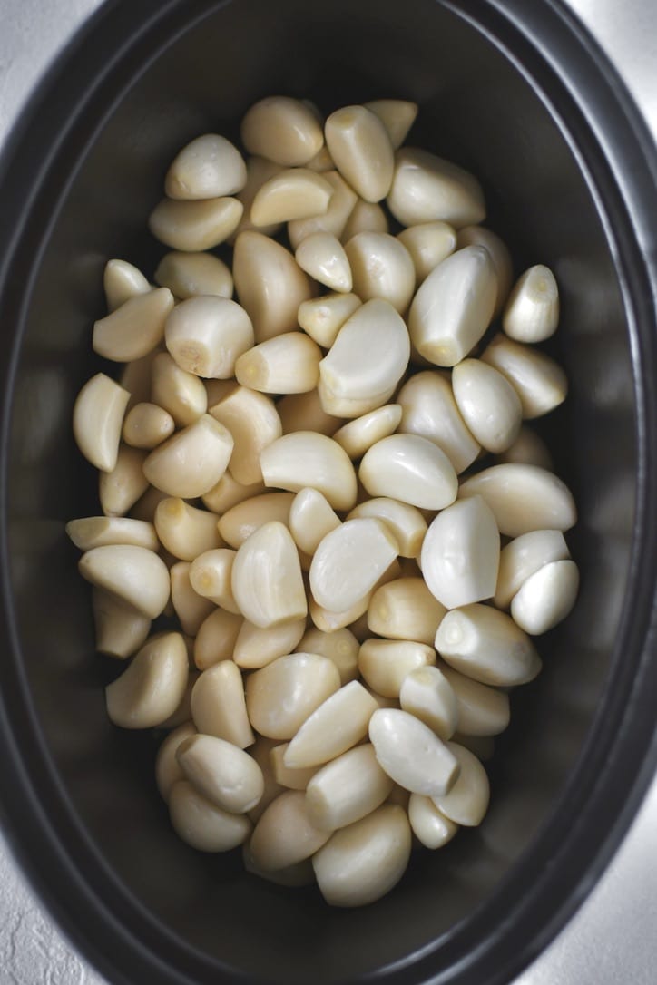 Garlic cloves in a cast iron pot before adding the herbs and olive oil.