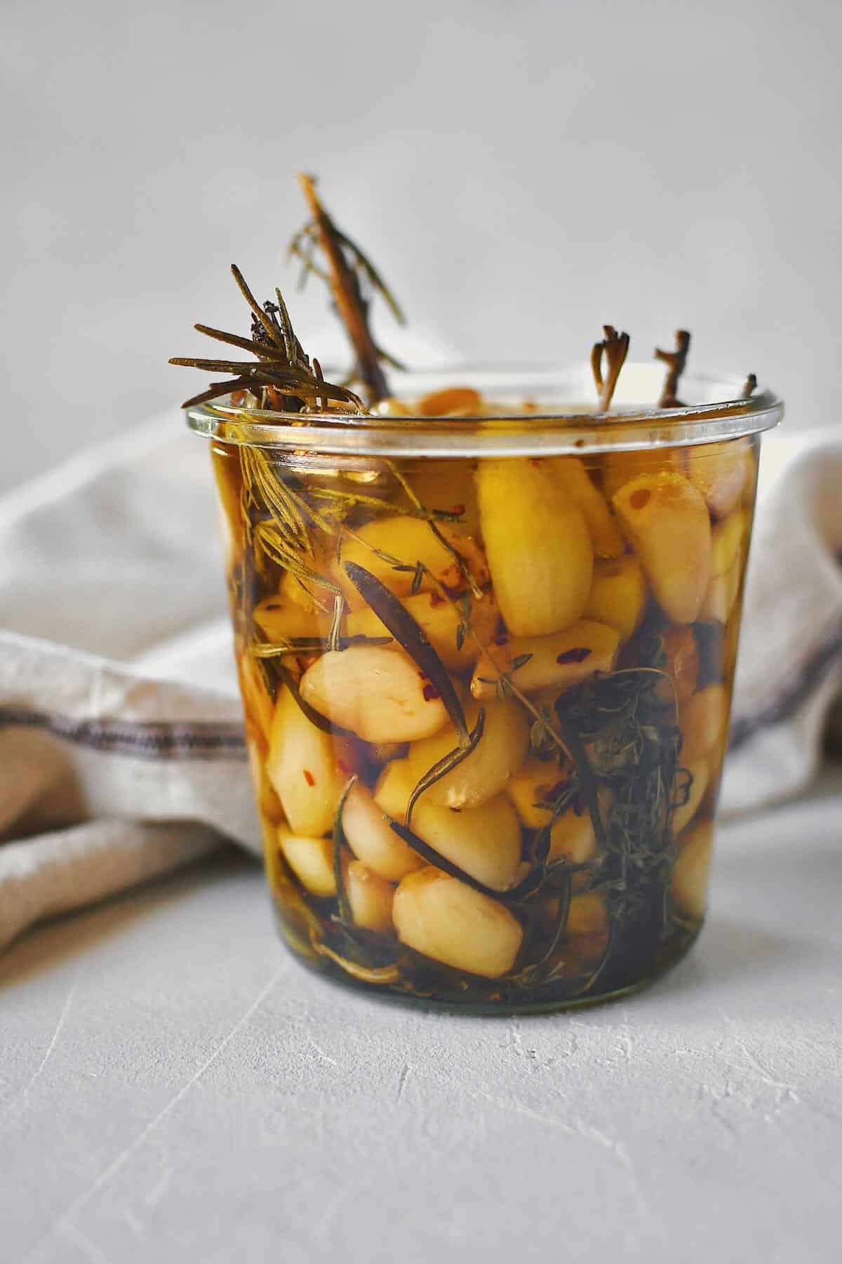 Garlic Confit in a jar covered with olive oil, ready to eat.