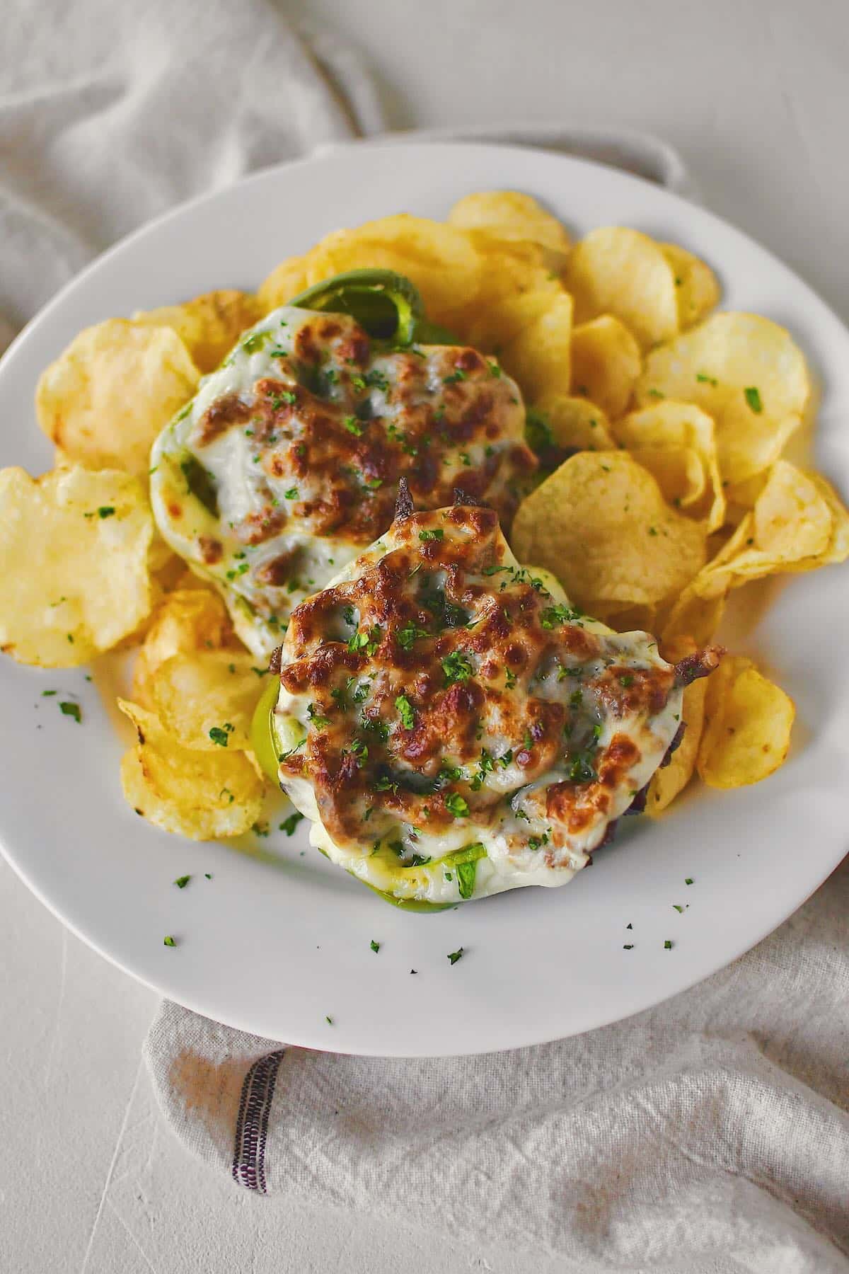 Philly Cheesesteak Stuffed Peppers on a plate ready to eat surrounded by potato chips.