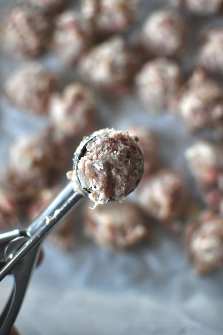 Portioning out the meatball mixture into tiny meatballs.