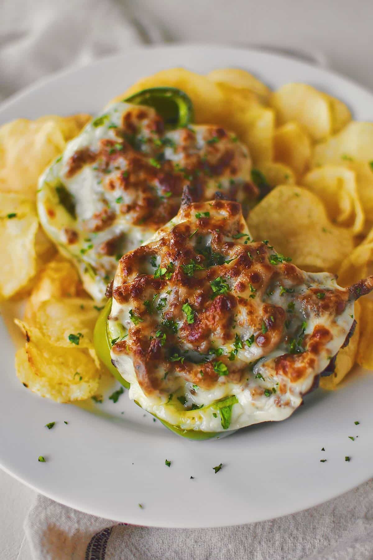 Philly Cheesesteak Stuffed Peppers on a plate ready to eat surrounded by potato chips.