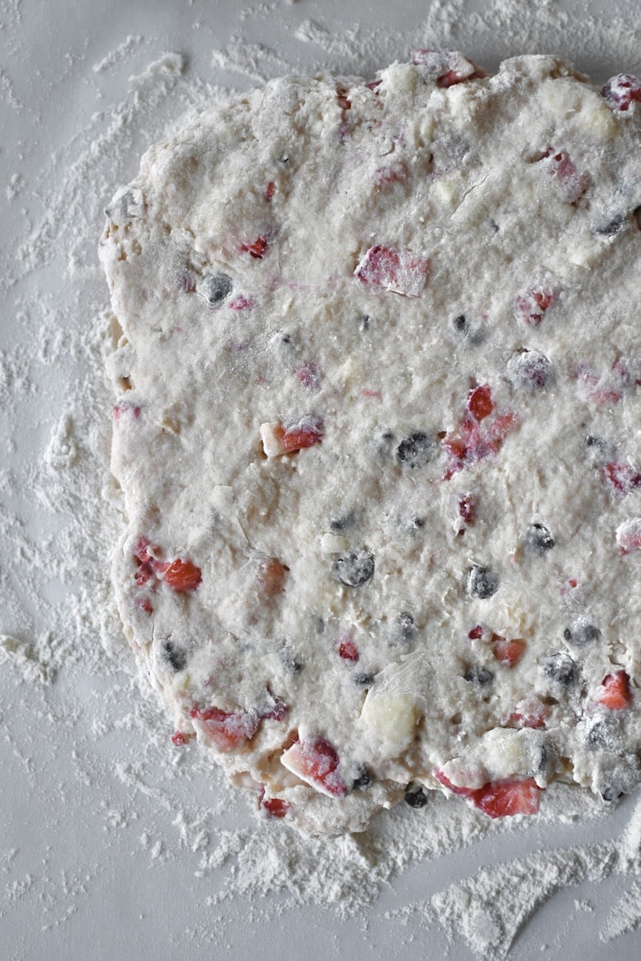 Scone dough turned out onto a well floured surface and flattened out.