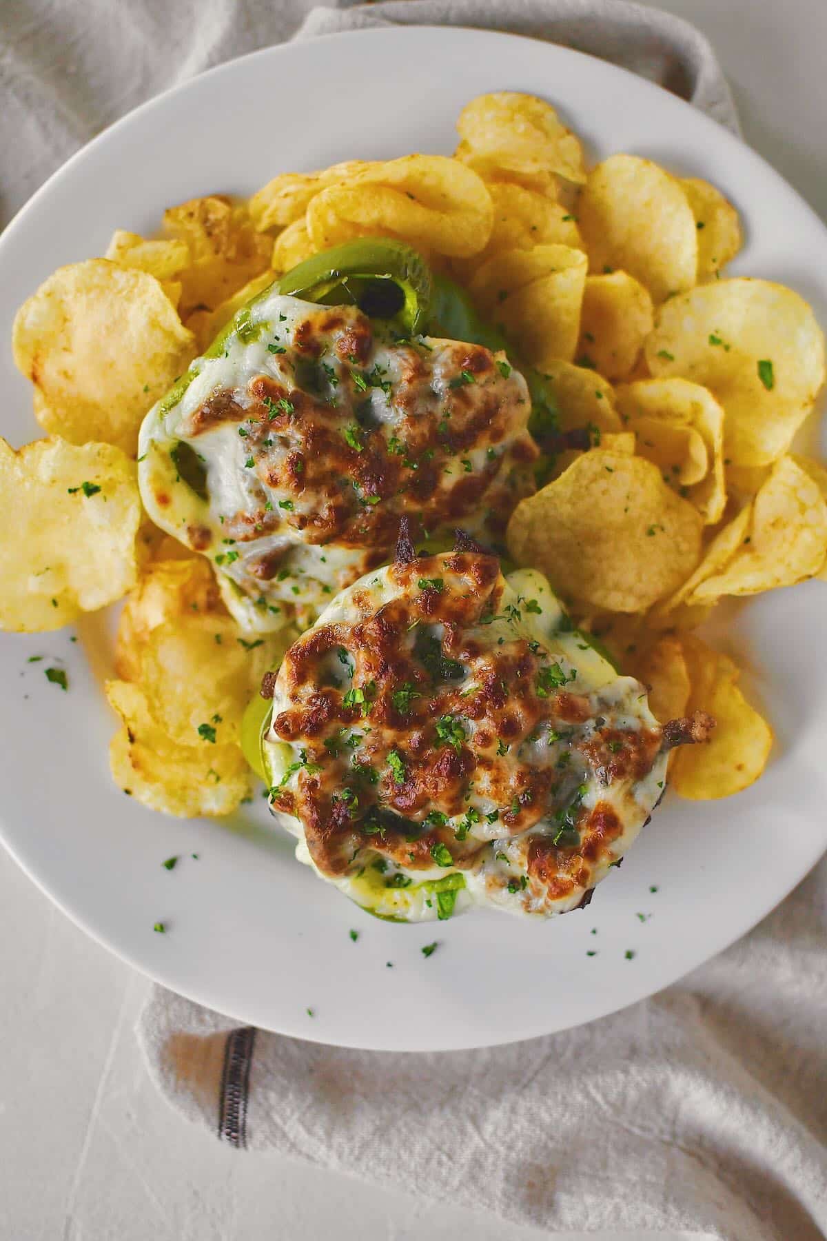 Philly Cheesesteak Stuffed Peppers on a plate ready to eat surrounded by potato chips.