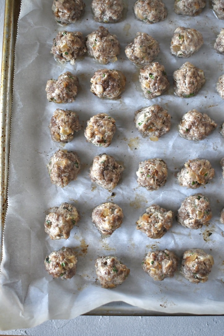 Portioned out meatball mixture into tiny meatballs, on a tray and rolled into uniform balls, baked till set.