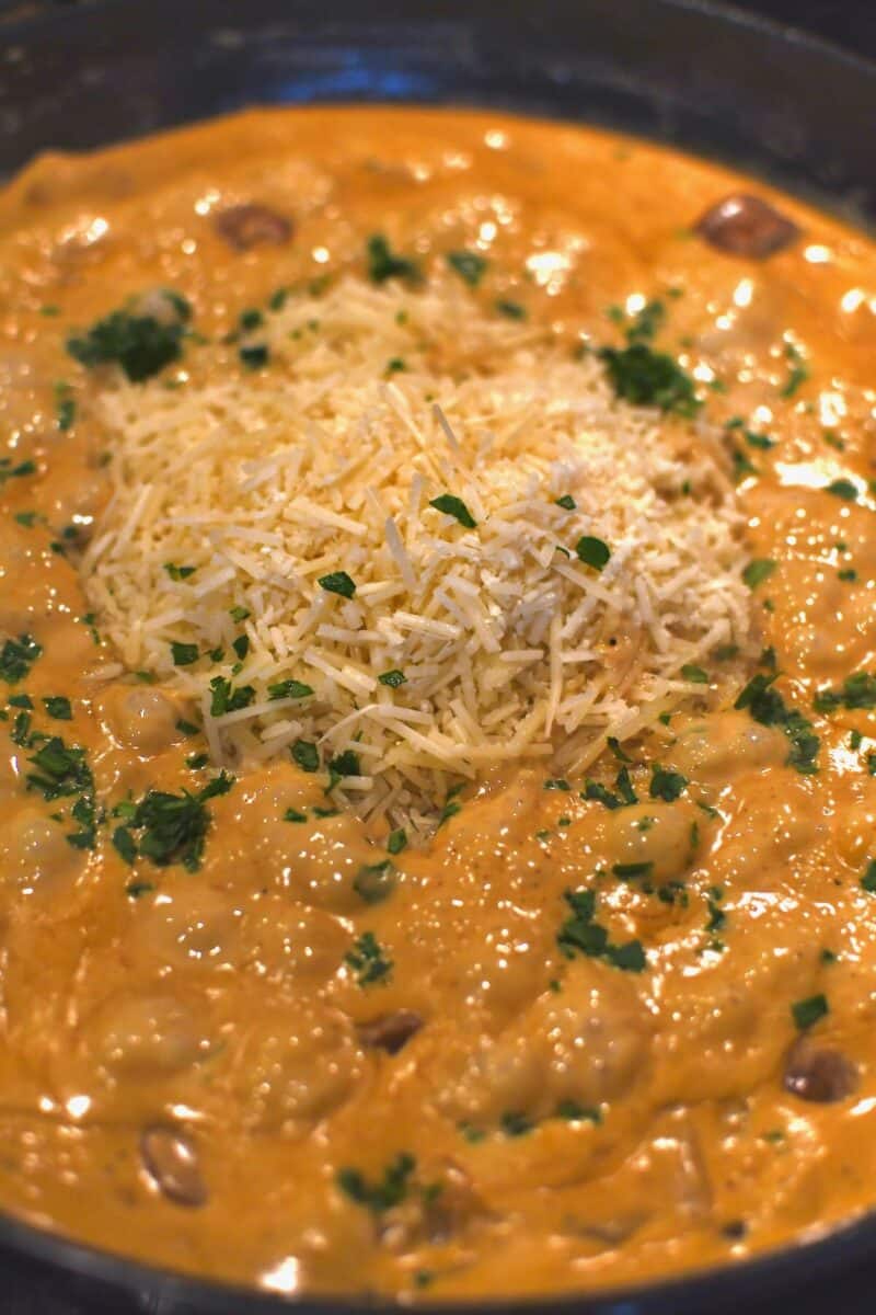 Adding the parmesan cheese and a pinch of parsley to the pan before the pasta.