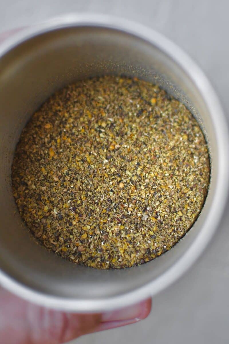 Placing the whole seeds and peppercorns in a spice grinder, after grinding.