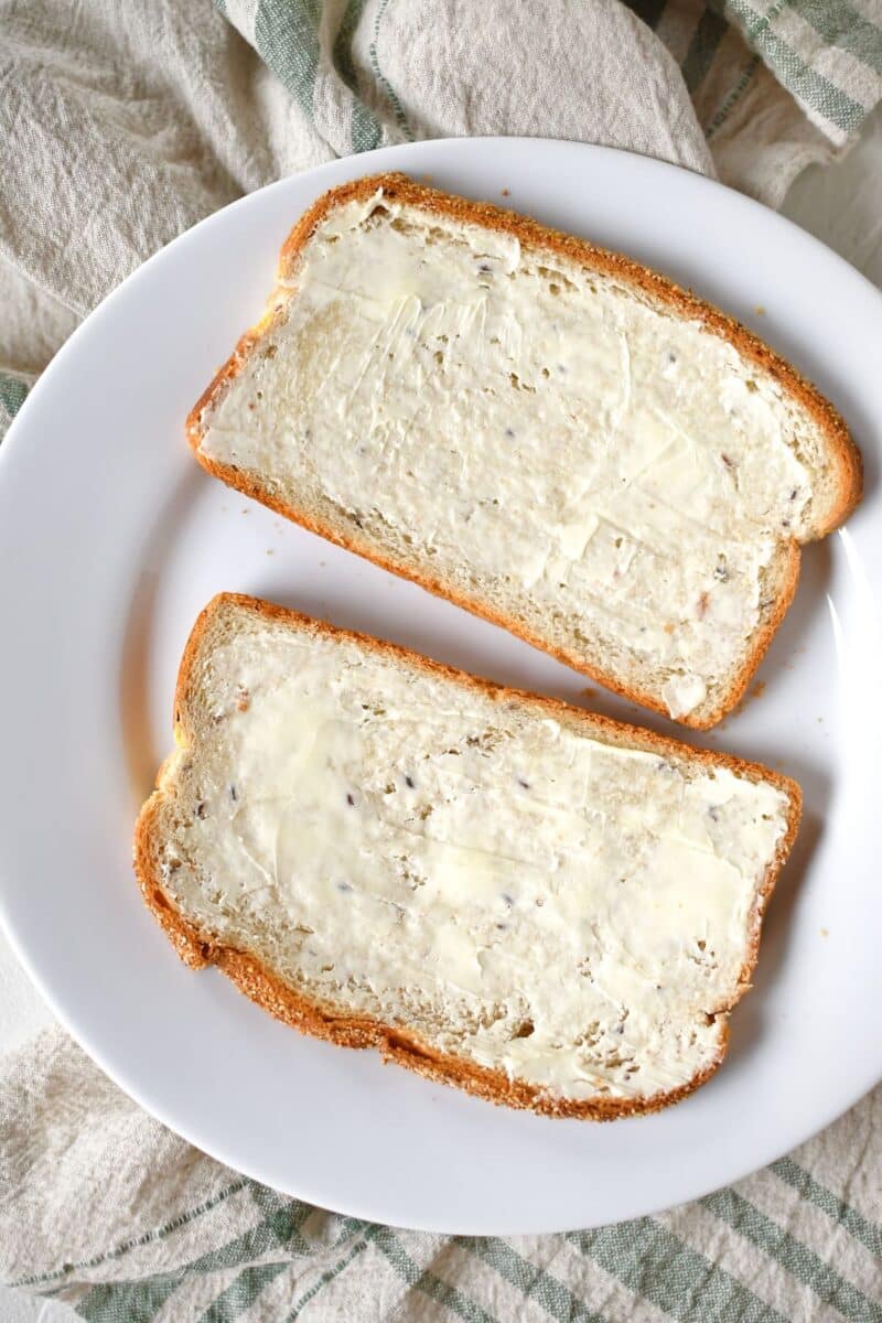 Buttering bread before toasting in a pan.