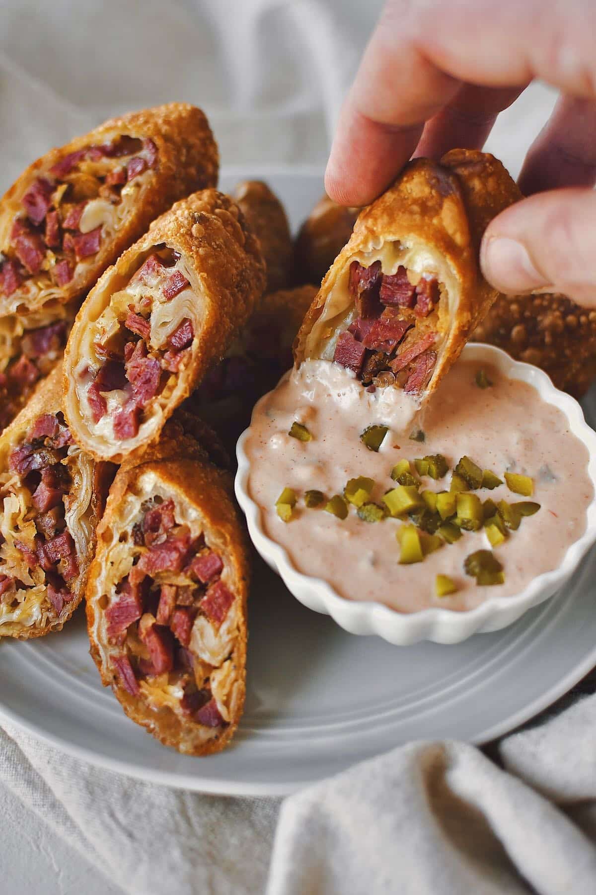 Dipping half a Reuben Egg Roll in Russian dressing, ready to eat it.