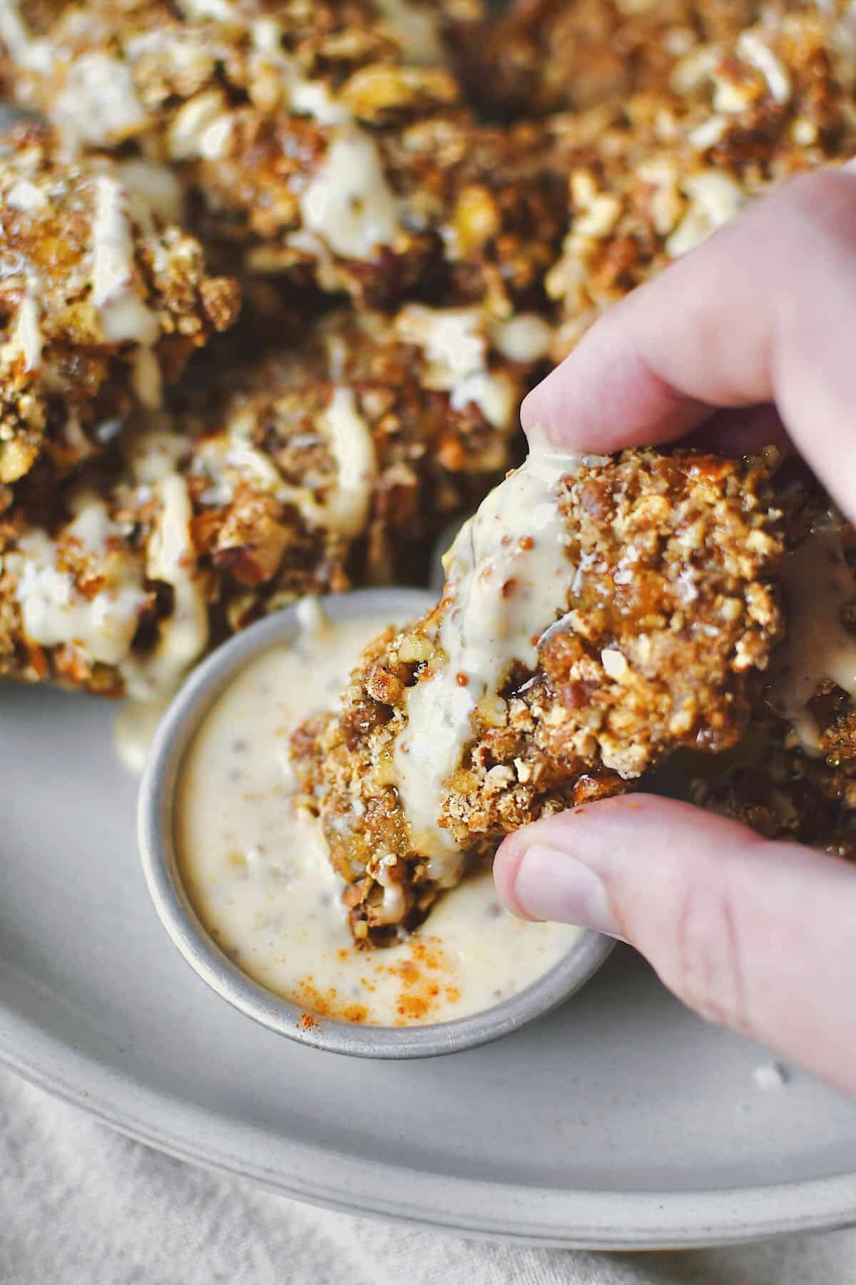 Dipping a piece of chicken in honey mustard sauce, ready to eat.